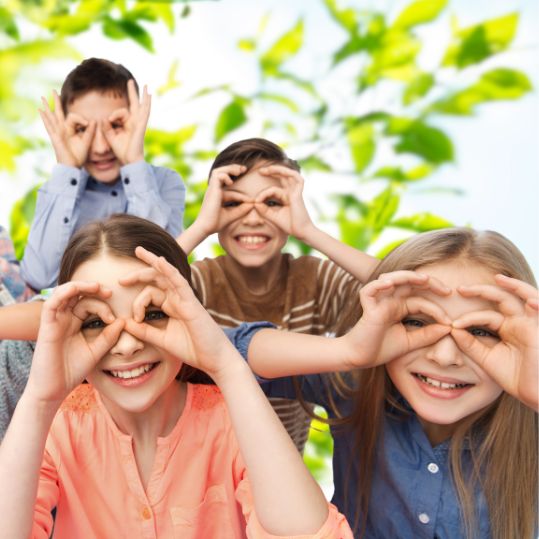 photo of four kids making glasses shapes with their hands over their eyes. they are all happy.